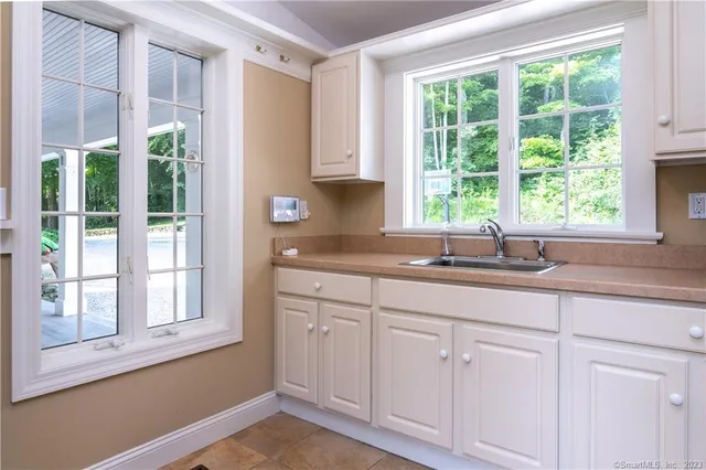 a kitchen with white cabinets and a window