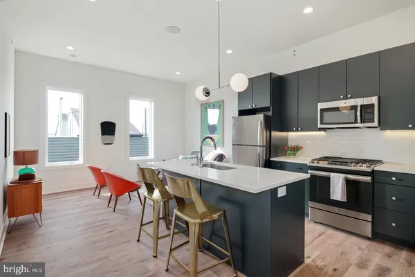 a kitchen with stainless steel appliances granite countertop a stove a refrigerator a kitchen island a sink dishwasher and white cabinets with wooden floor