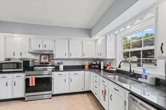 a kitchen with granite countertop white cabinets and white stainless steel appliances