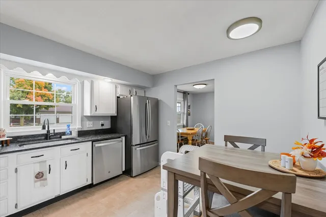 a kitchen with a refrigerator a stove a sink and dishwasher with white cabinets