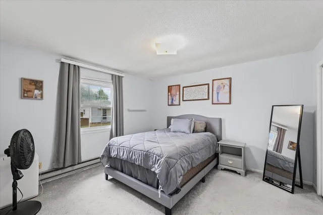 a bedroom with a bed chair and mirror