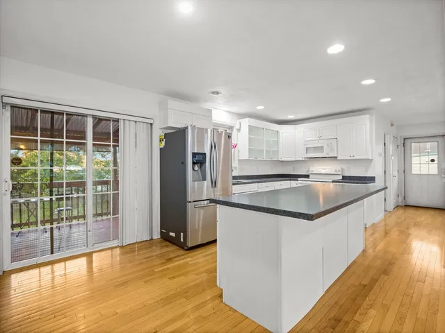 a kitchen with stainless steel appliances granite countertop a refrigerator a sink a stove and a wooden floors