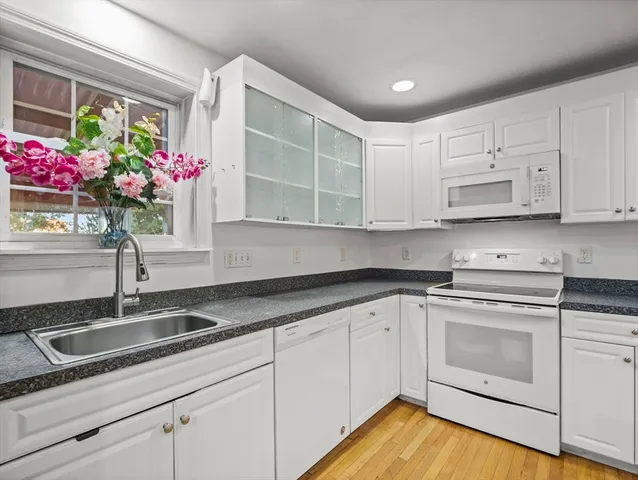 a kitchen with stainless steel appliances granite countertop a sink a stove and white cabinets