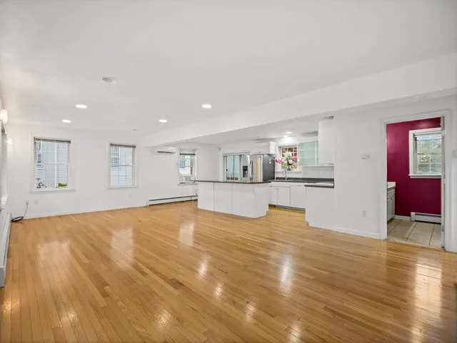 a view of a kitchen with kitchen island a sink wooden floor and a refrigerator