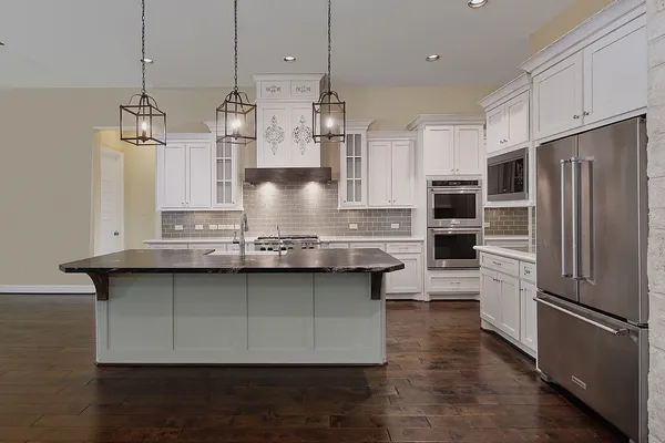 a kitchen with stainless steel appliances granite countertop a refrigerator a stove and a sink