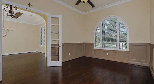 an empty room with wooden floor cabinet and windows