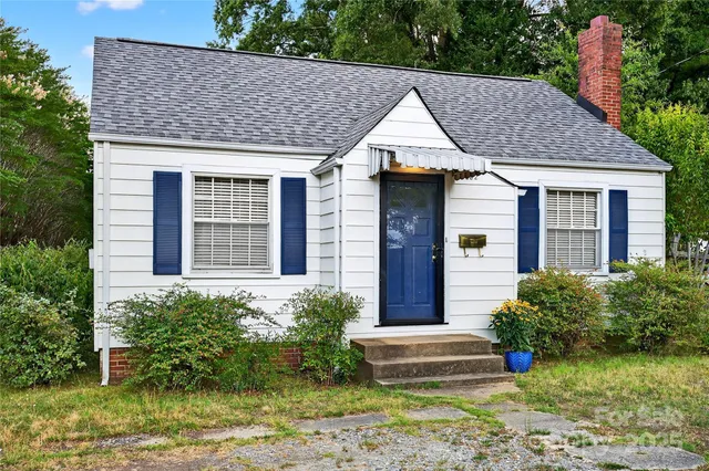 a view of a house with a yard plants and large tree