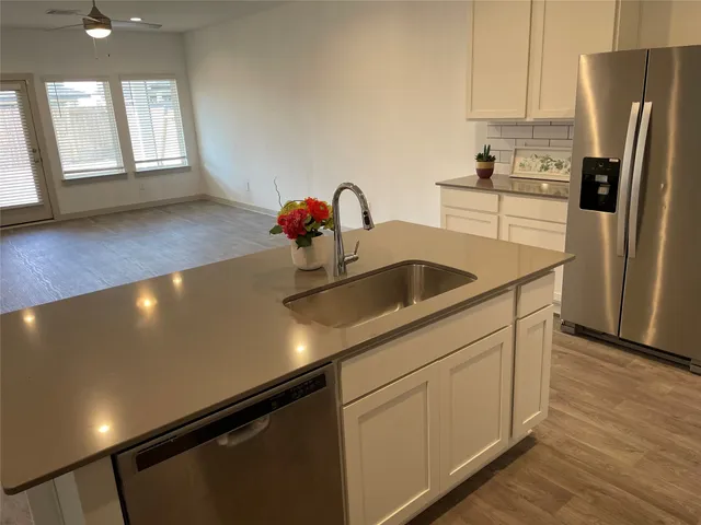a kitchen with stainless steel appliances a sink a refrigerator and a window