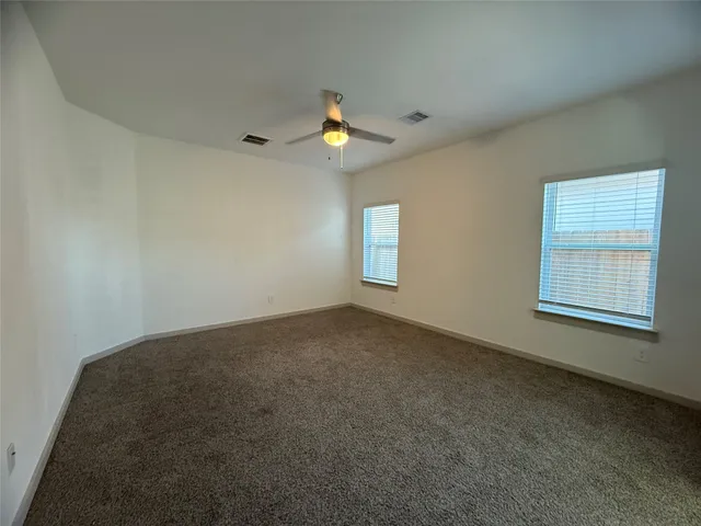 an empty room with windows and fan