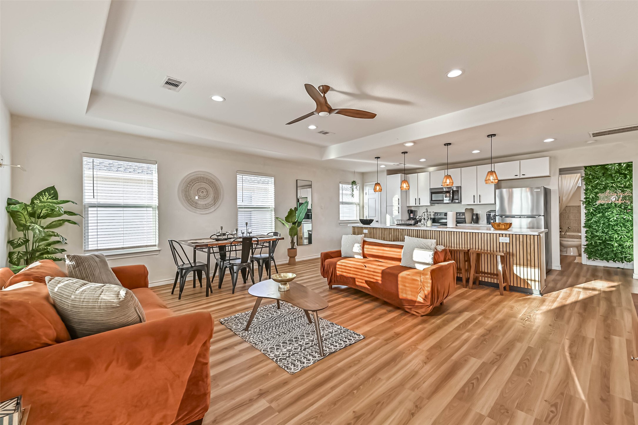 a living room with furniture kitchen view and a wooden floor