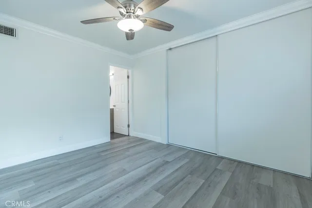 an empty room with wooden floor and fan