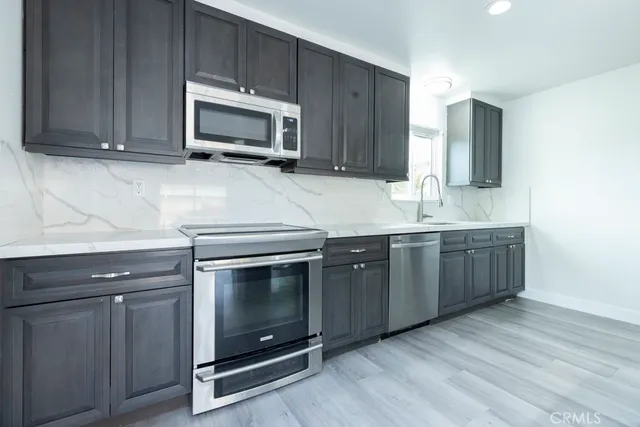 a kitchen with granite countertop a stove microwave and sink