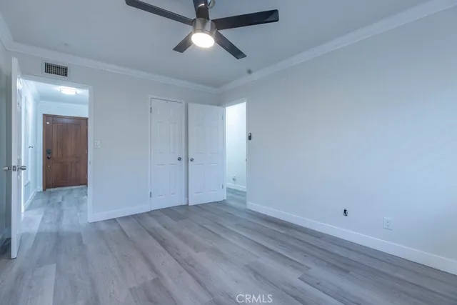 an empty room with wooden floor and ceiling fan