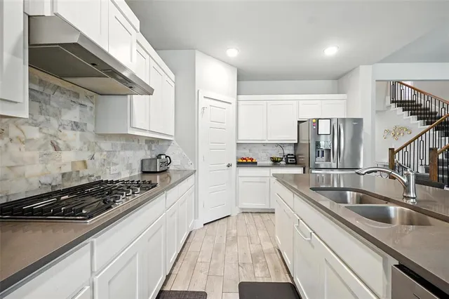 a kitchen with stainless steel appliances a sink a stove and cabinets