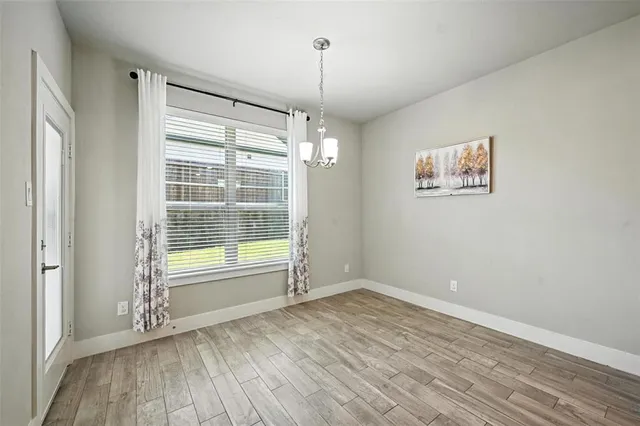 a view of an empty room with a window and hardwood floor