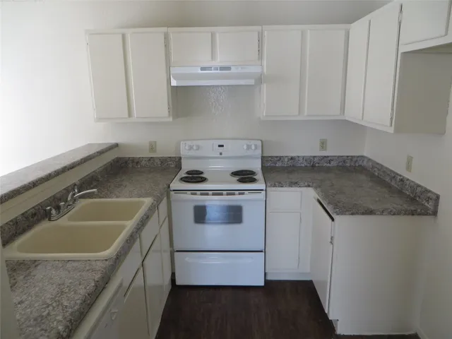 a kitchen with granite countertop a sink stove and cabinets