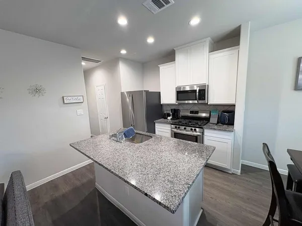a kitchen with stainless steel appliances granite countertop a stove refrigerator and a microwave
