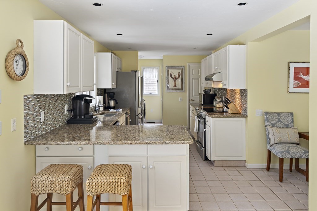 64 Jernegan Pond Road Edgartown, MA 02539 - Photo 9 of 25 a kitchen with stainless steel appliances granite countertop a sink a stove a refrigerator cabinets and chairs