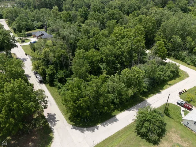 an aerial view of residential house with outdoor space and trees all around