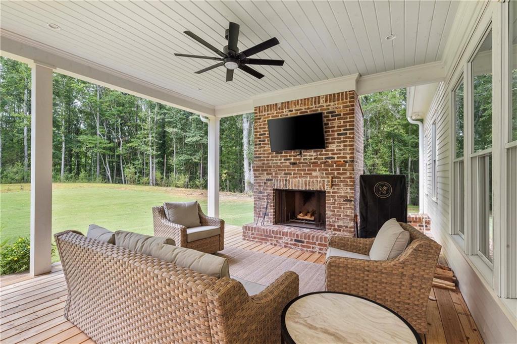 9311 Waterworks Road Chattahoochee Hills, GA 30268 - Photo 53 of 57 a living room with furniture a fireplace a large window and a flat screen tv