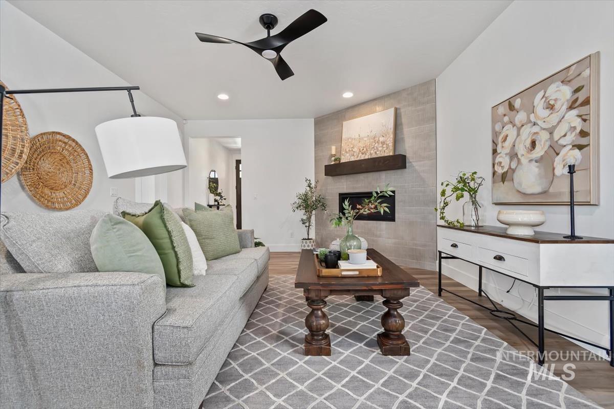 5897 West Riva Capri Street Meridian, ID 83646 - Photo 11 of 50 Living area featuring a floor-to-ceiling tiled fireplace with a dark wood mantel, a modern ceiling fan, and recessed lighting