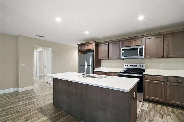 a kitchen with stainless steel appliances granite countertop a sink and stove top oven with wooden floor