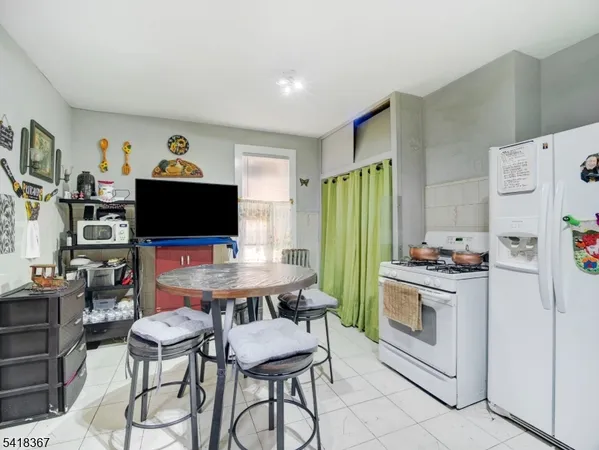 a kitchen with stainless steel appliances a stove a refrigerator and a dining table with wooden floor