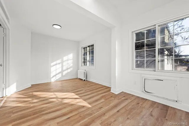 a view of an empty room with a window and wooden floor