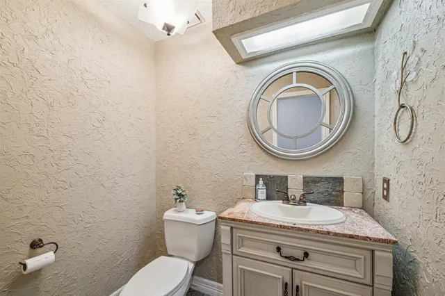 a bathroom with a granite countertop toilet sink and mirror