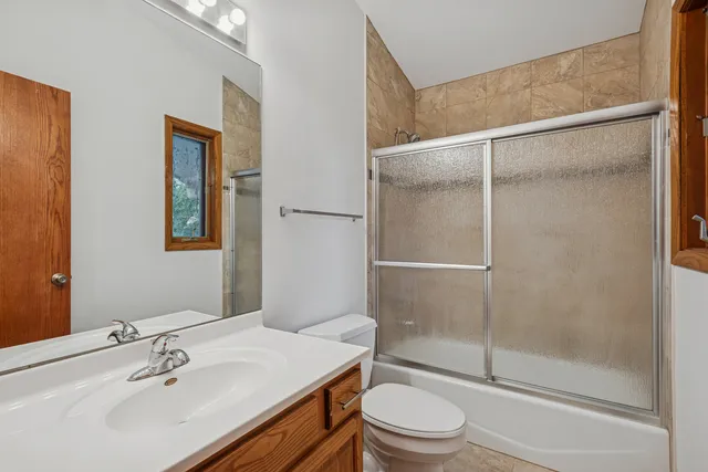 a bathroom with a granite countertop sink toilet and mirror