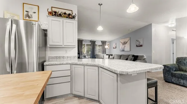 a kitchen with stainless steel appliances granite countertop a stove top oven a refrigerator a sink and a dining table with chairs