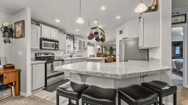 a kitchen with kitchen island a dining table chairs stainless steel appliances and cabinets