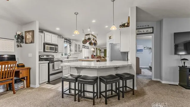 a kitchen that has a lot of white cabinets and stainless steel appliances