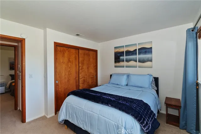 a view of a white house with a small yard and large trees