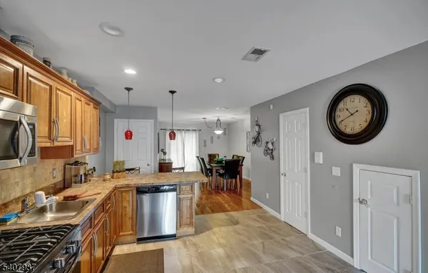 a kitchen with stainless steel appliances granite countertop a stove top oven a sink a dining table and chairs with wooden floor