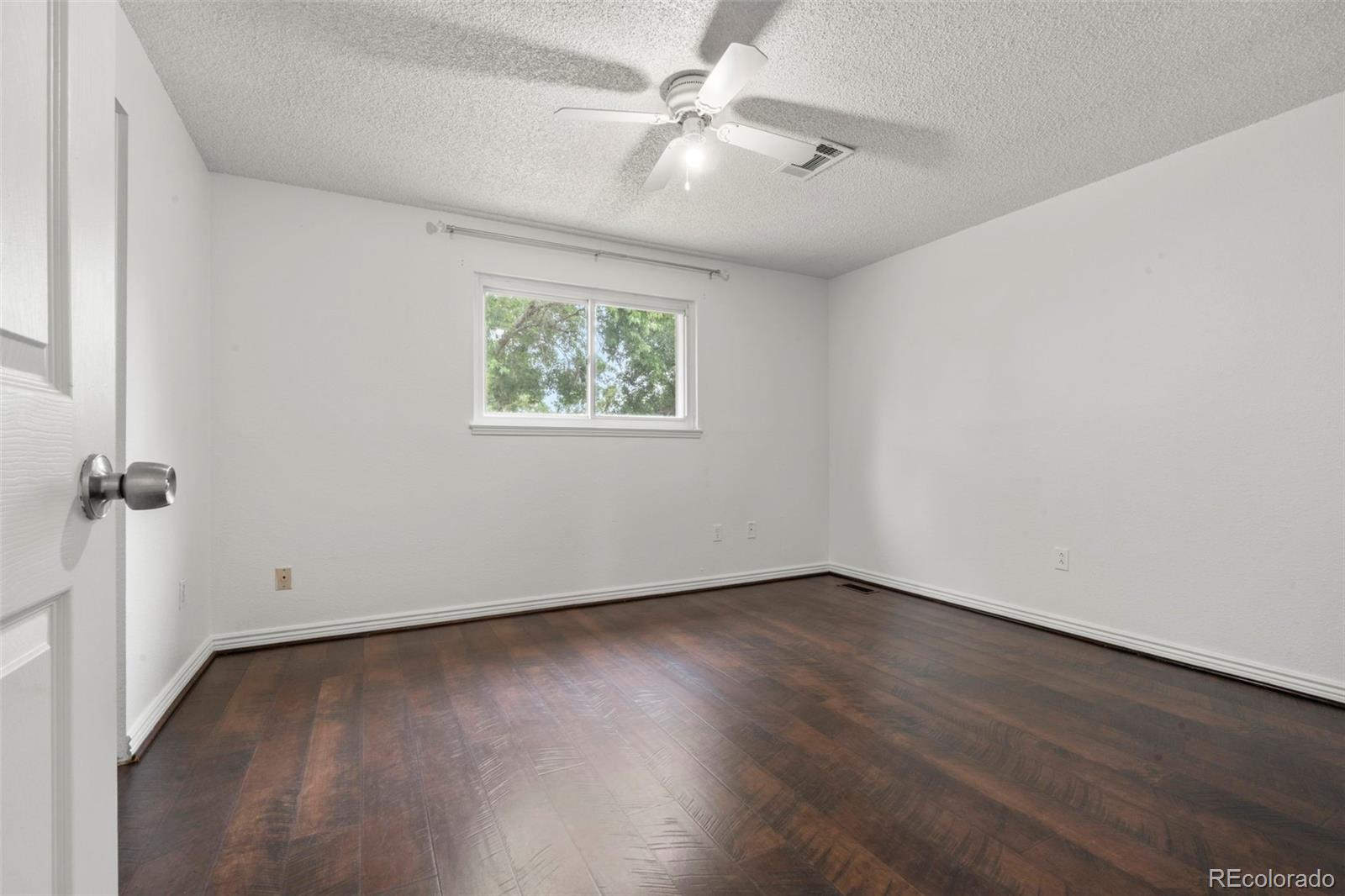 5167 Sable Street Denver, CO 80239 - Photo 11 of 27 an empty room with wooden floor and ceiling fan