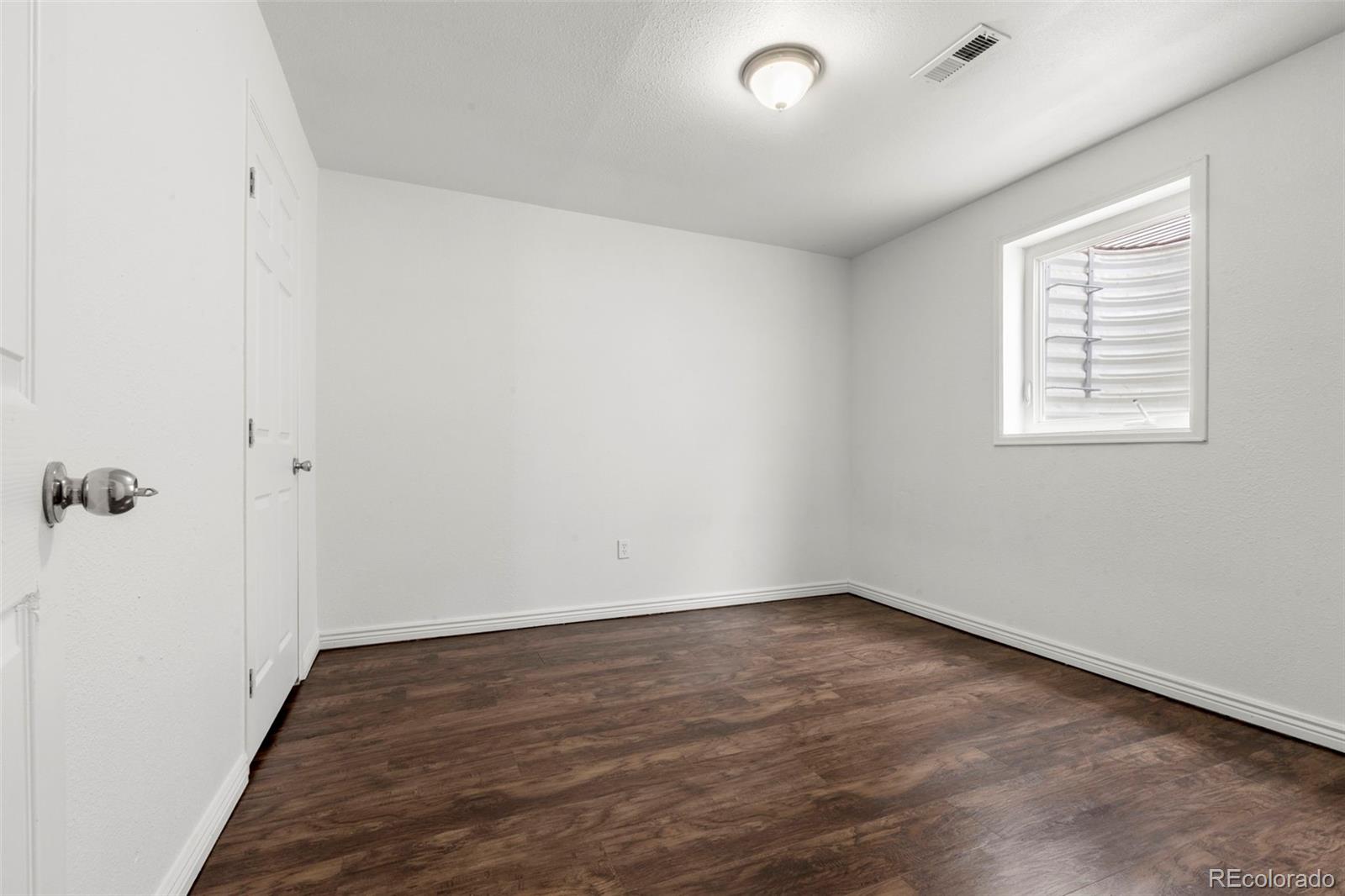 5167 Sable Street Denver, CO 80239 - Photo 13 of 27 an empty room with wooden floor and windows