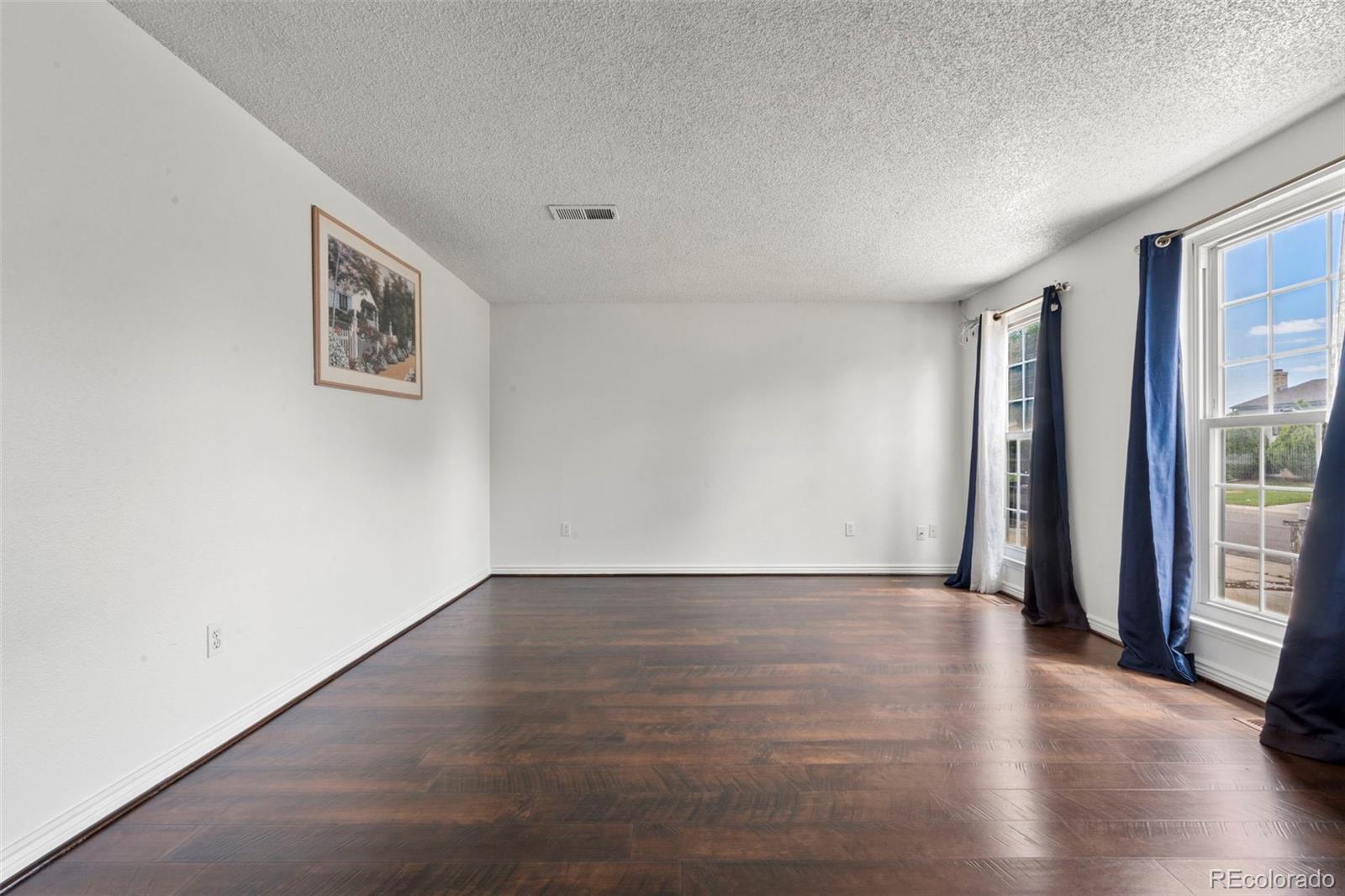 5167 Sable Street Denver, CO 80239 - Photo 6 of 27 an empty room with wooden floor and windows