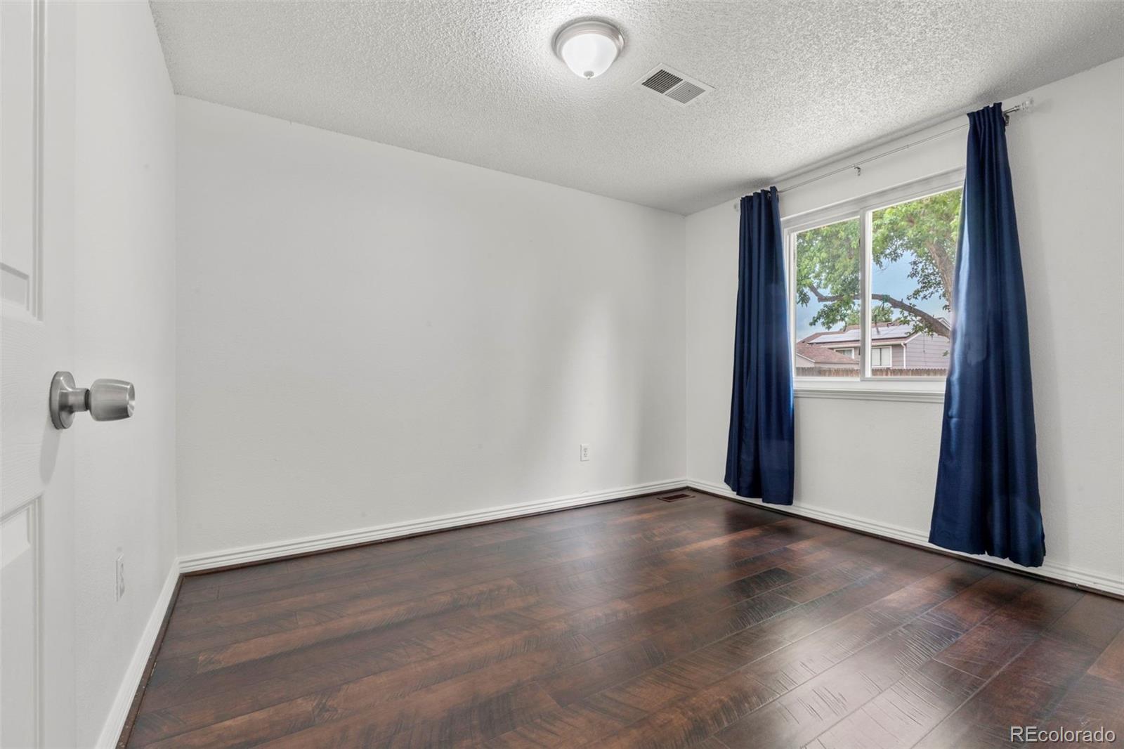 5167 Sable Street Denver, CO 80239 - Photo 10 of 27 an empty room with wooden floor and windows