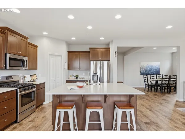 a kitchen with stainless steel appliances granite countertop a stove a refrigerator a kitchen island a table and chairs