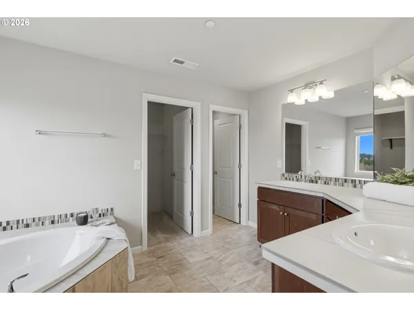 a bathroom with a tub double vanity sink and mirror