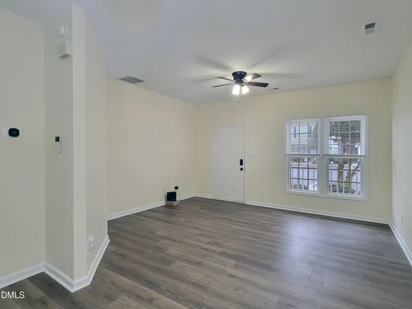 a view of an empty room with a window and wooden floor