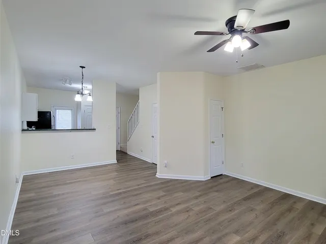 an empty room with wooden floor chandelier fan and windows