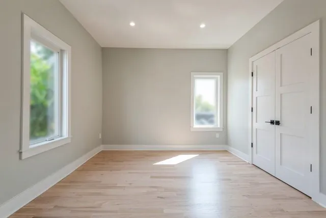 a view of an empty room with wooden floor and a window