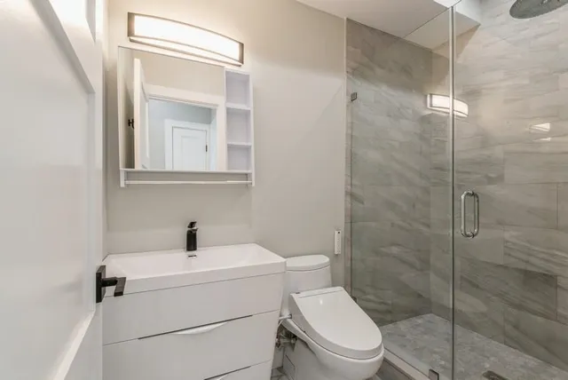 a bathroom with a toilet sink vanity and shower