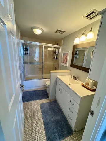 a bathroom with a sink a toilet a mirror and shower