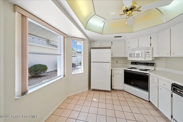 a kitchen with a refrigerator a stove top oven and a potted plant
