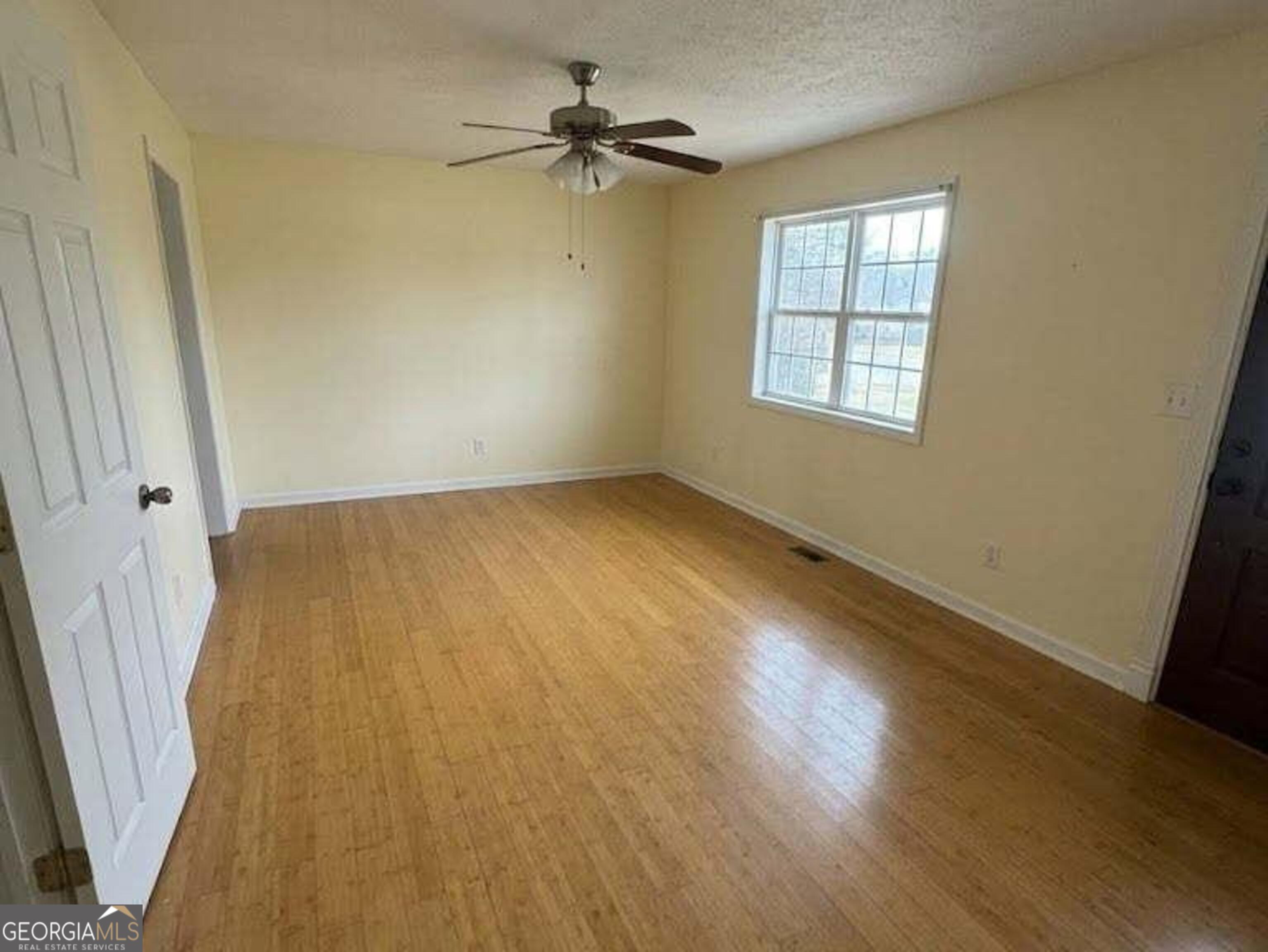 6052 Pinecreek Road Forest Park, GA 30297 - Photo 3 of 12 an empty room with wooden floor fan and windows