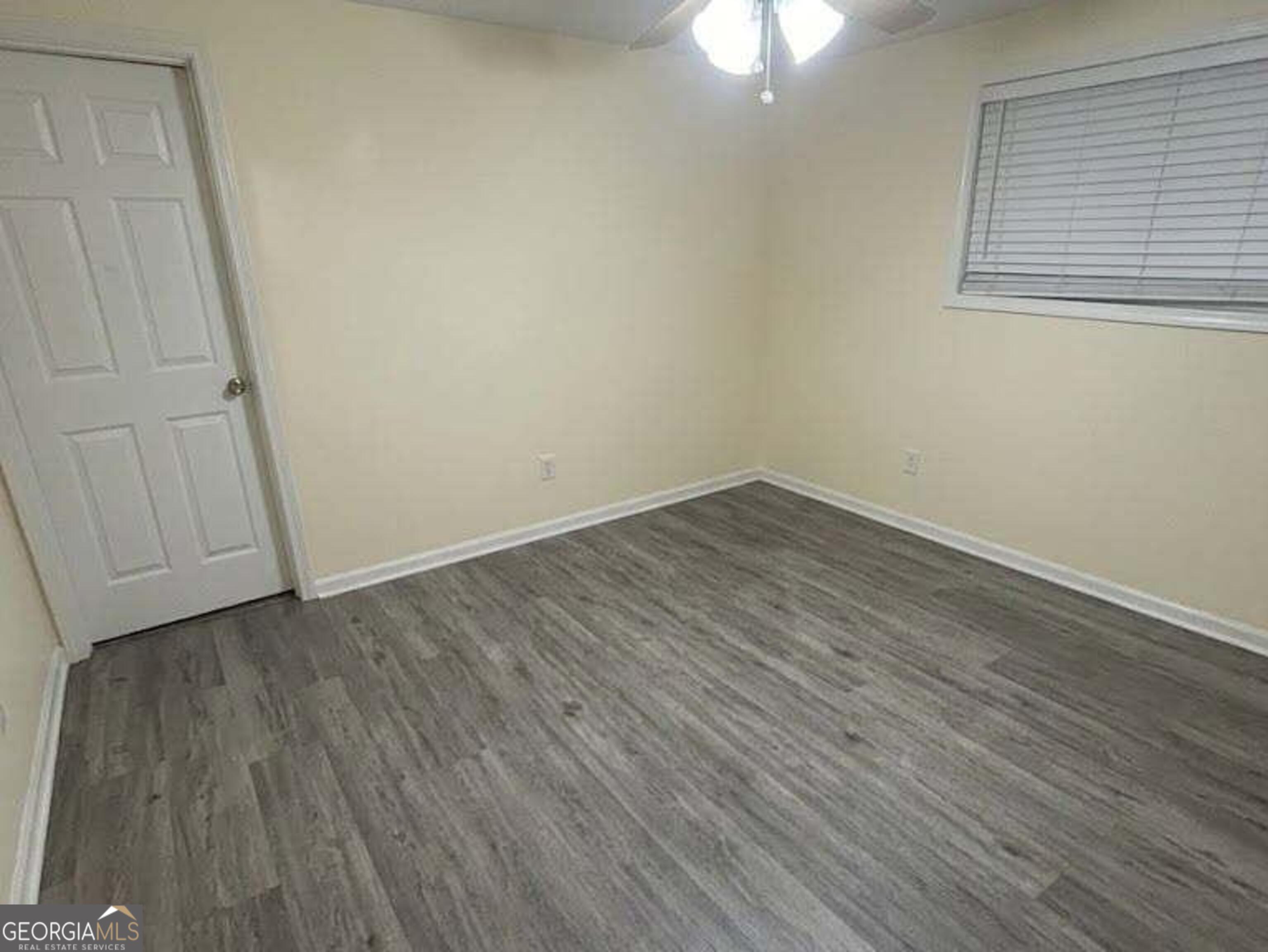 6052 Pinecreek Road Forest Park, GA 30297 - Photo 5 of 12 a view of an empty room with wooden floor and a window