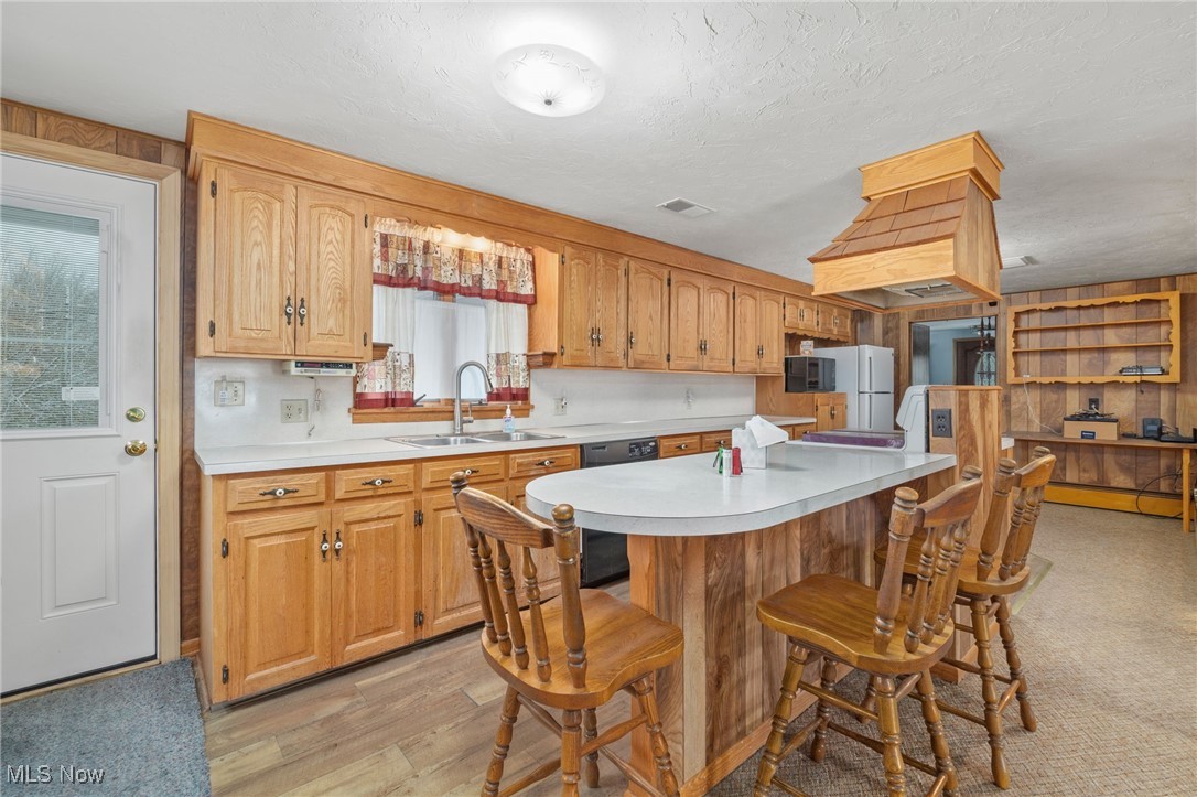 9952 Sterling Road Rittman, OH 44270 - Photo 5 of 28 Kitchen with light countertops, a kitchen bar, light wood-type flooring, a textured ceiling, and black appliances